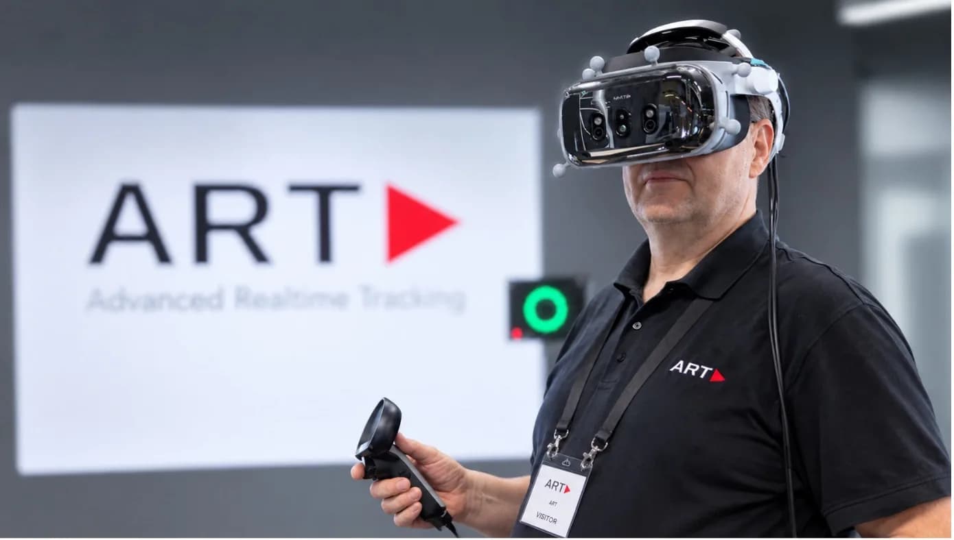 Mann mit getracktem VR-Headset und Controller vor dem ART-Logo